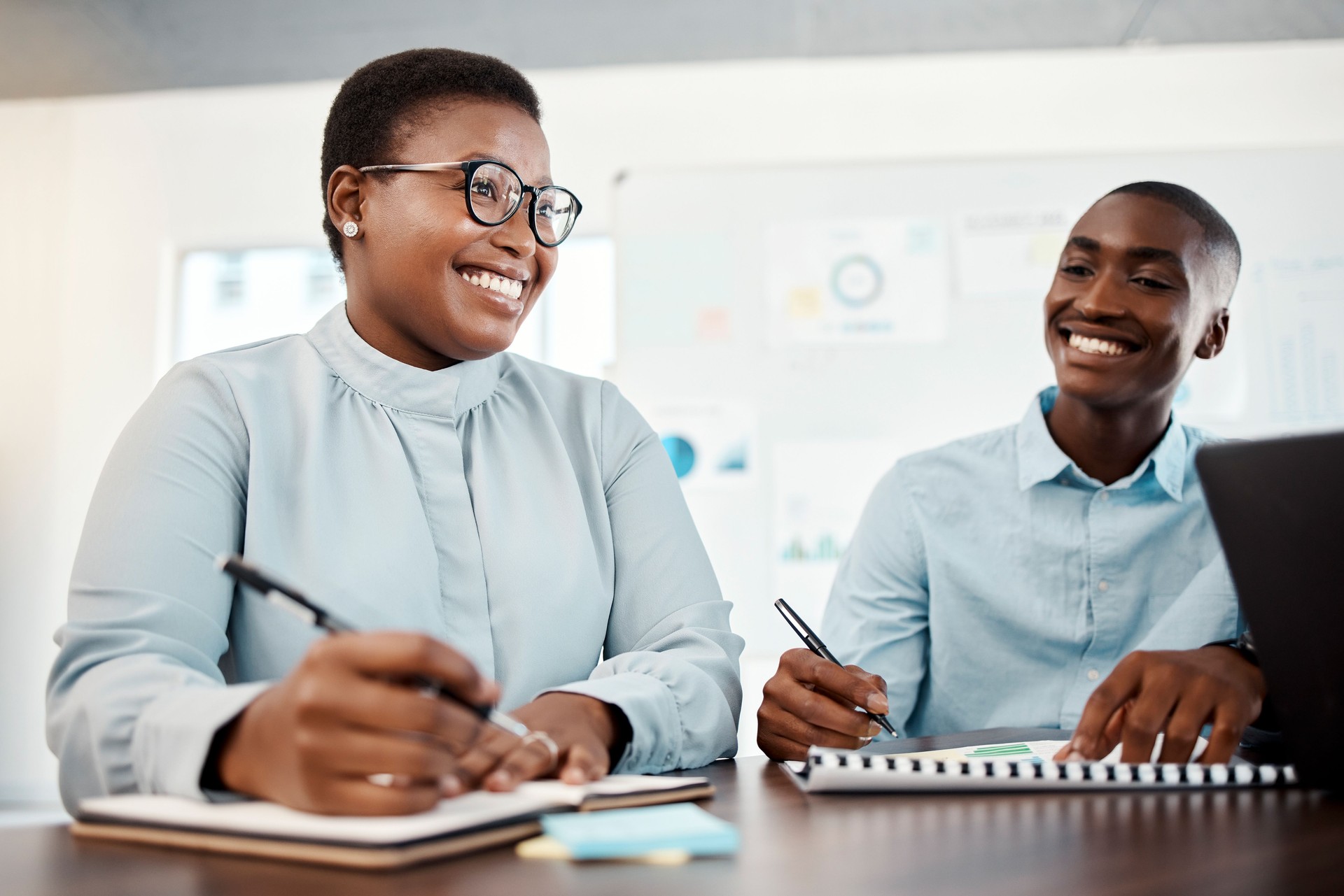 Black woman, man and writing with planning, strategy and development of company growth in advertising meeting. Business people with teamwork, business meeting and b2b support for startup project idea